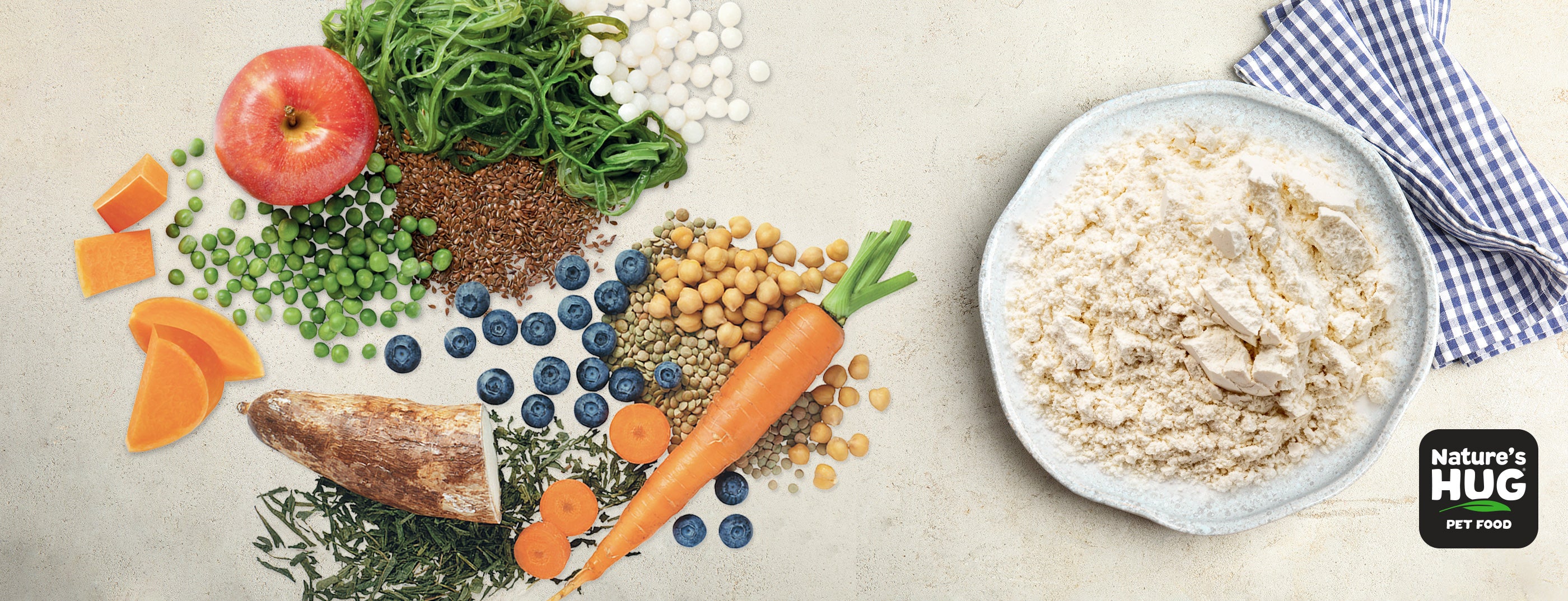 An assortment of wholesome ingredients arranged artfully. A blue and white checkered cloth is partially visible. Central is a bowl of flour, surrounded by fresh ingredients including an apple, green peas, kelp, pumpkin pieces, flaxseed, tapioca pearls, carrots, and other vegetables.