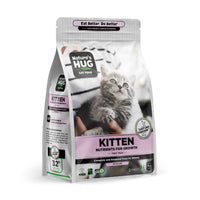 A package of Kitten, Nutrients for Growth Formula Cat Food "Nature's Hug" bag stands upright, showcasing a tabby cat being petted by a person. The label reads "Nutrients for Growth," emphasizing complete nutrition for kittens.