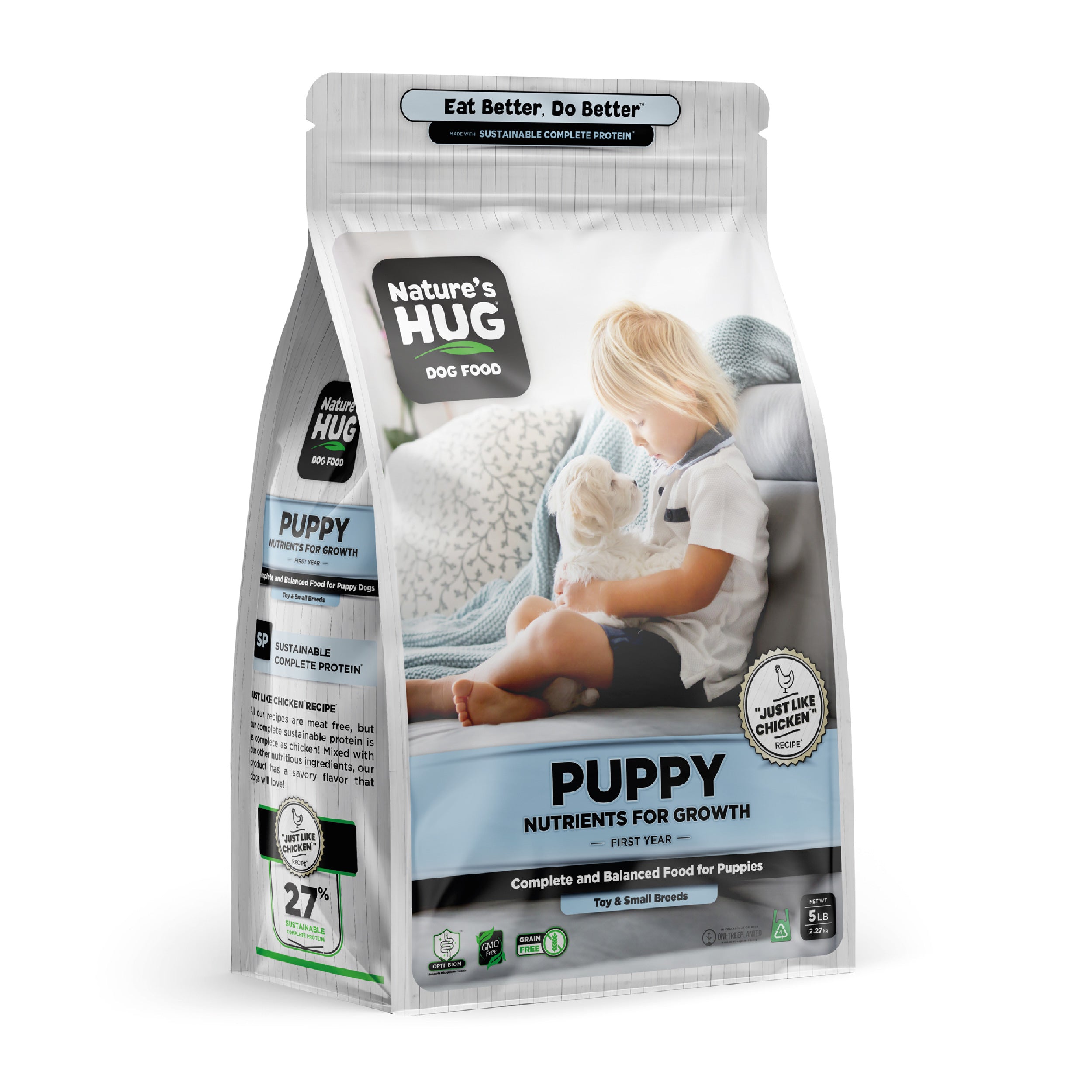 The image features a bag of Puppy, Nutrients for Growth Formula Dog Food for Toy & Small Breeds "Nature's Hug". The packaging highlights that it offers complete and balanced nutrition for growth in the first year. In the foreground, a child with short blonde hair sits on a couch, gently holding a small white puppy. The background shows a cozy setting with patterned cushions.